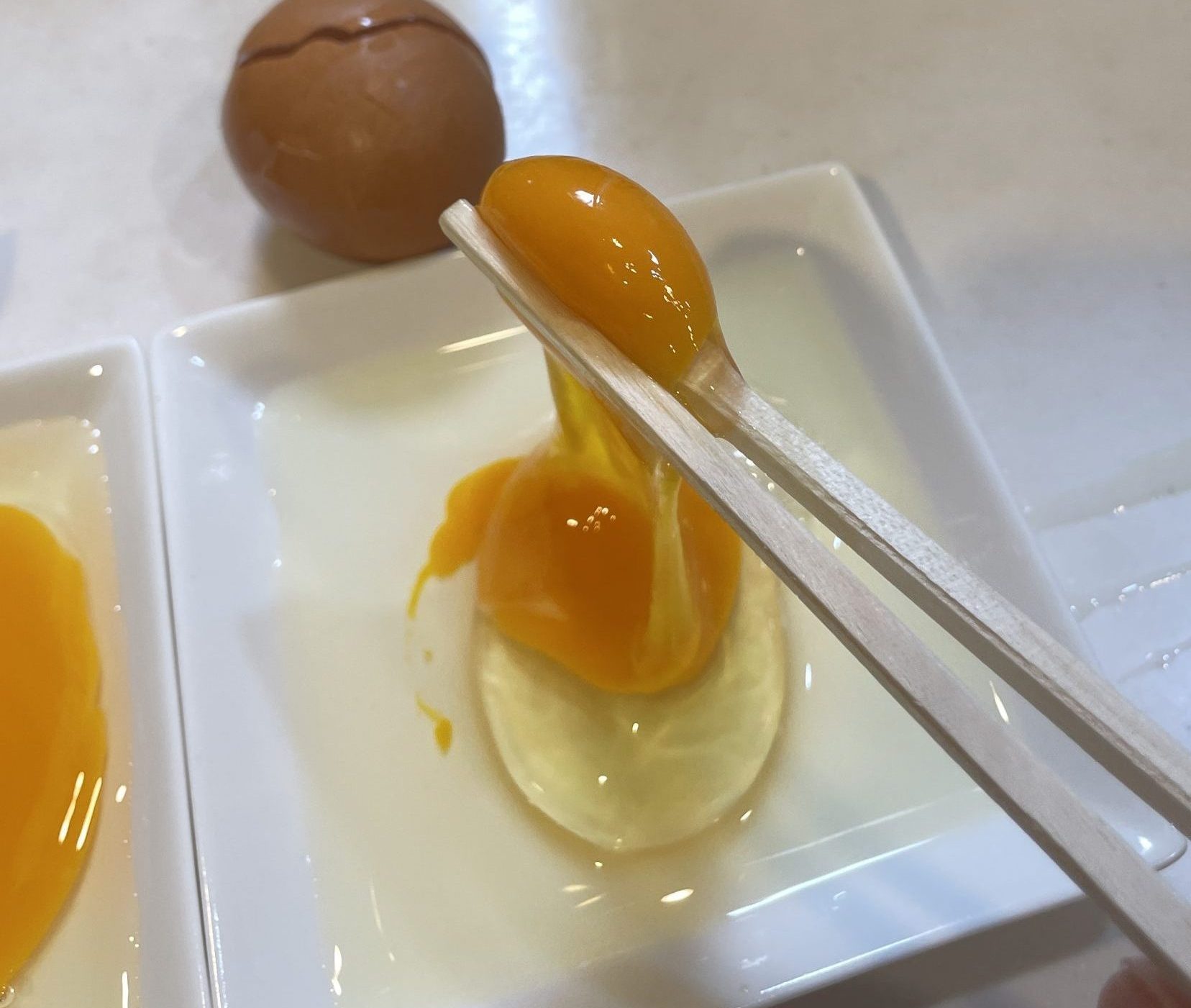 箸でつまんで持ち上げた卵の黄身